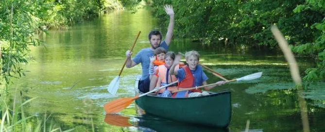 Eine Gruppe paddelt im Kanu den Fluss hinunter.