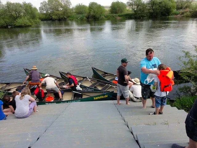 kanuverleih-kanutouren-kanuvermietung-kanuta-17 Eine Gruppe von Menschen steht mit Kanus auf Stufen neben einem Fluss.