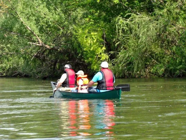 kanuverleih-kanutouren-kanuvermietung-kanuta-20 Drei Personen paddeln mit einem Kanu einen Fluss hinunter.