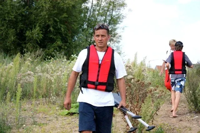 kanuverleih-kanutouren-kanuvermietung-kanuta-26 Ein Mann in einer Schwimmweste geht einen Feldweg entlang.
