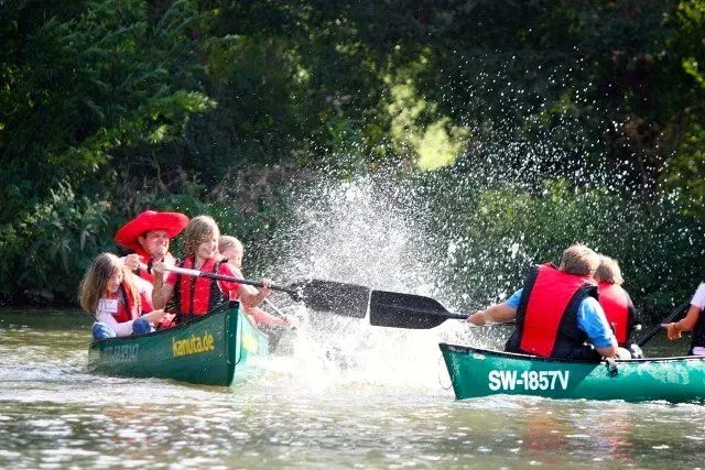kanuverleih-kanutouren-kanuvermietung-kanuta-36 Eine Gruppe von Menschen paddelt in einem Kanu auf einem Fluss.
