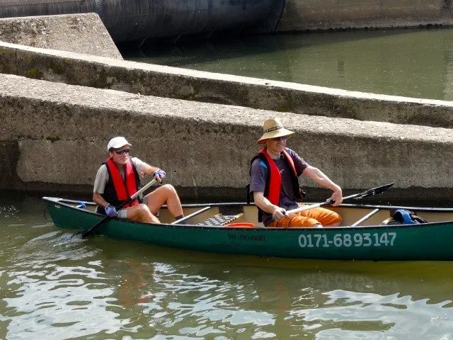 Zwei Personen paddeln mit einem Kanu durch einen Kanal.