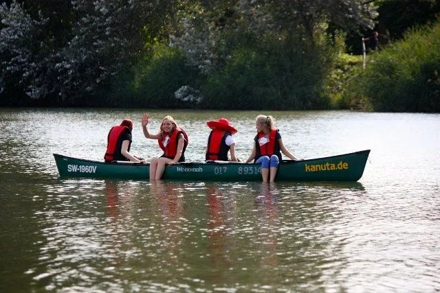 Drei Kinder in einem Kanu auf einem See.