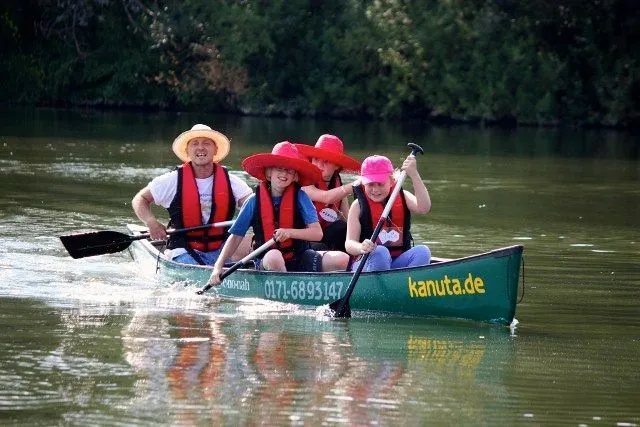 Eine Gruppe von Menschen paddelt in einem Kanu auf einem Fluss.