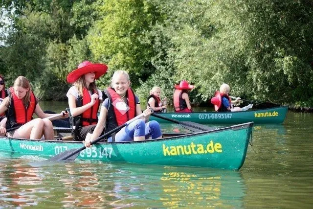 Eine Gruppe von Menschen paddelt in einem Kanu auf einem Fluss.