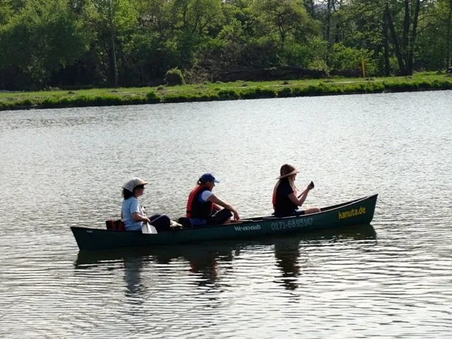Drei Personen in einem Kanu auf einem See.