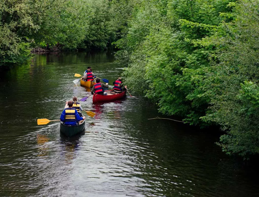 Eine Gruppe von Menschen, die an Kanutouren einen Fluss hinunter teilnehmen.